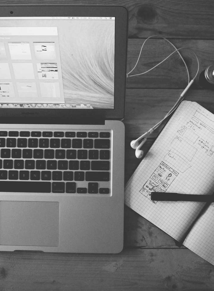 Open notebook and laptop with sketches on a desk